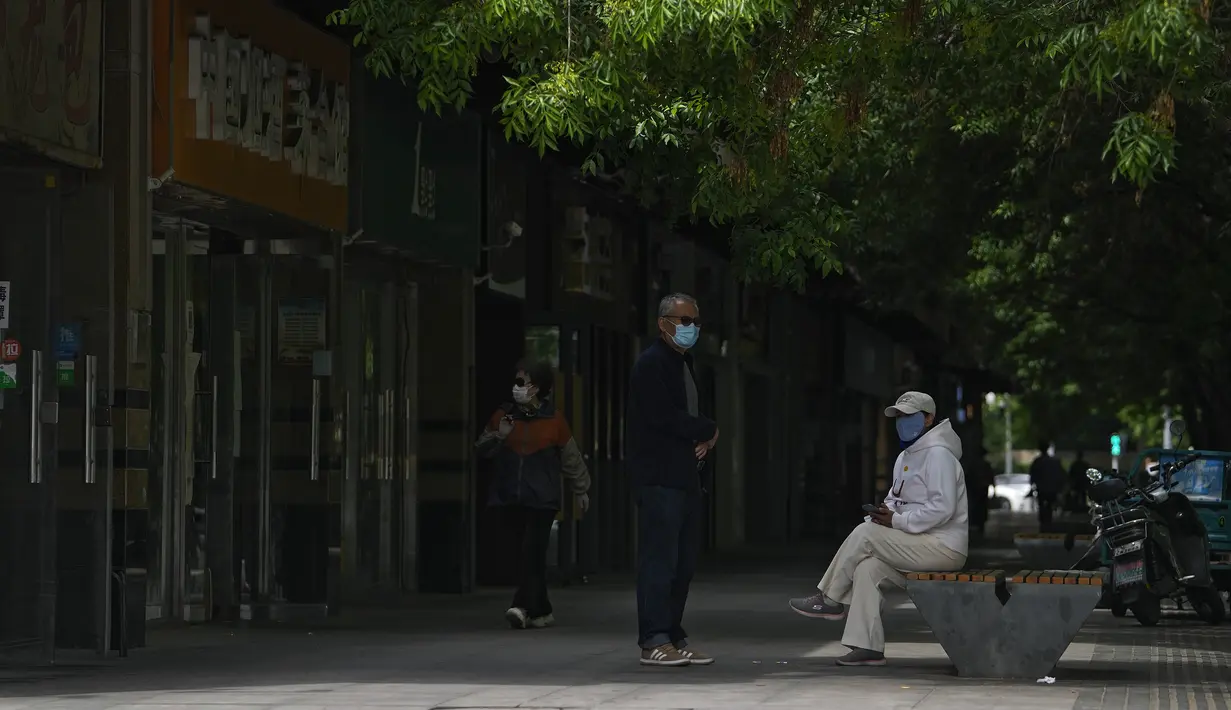 <p>Warga yang memakai masker beristirahat di dekat toko ritel yang tutup setelah perintah penutupan bisnis yang tidak penting dan meminta orang untuk bekerja di rumah di distrik Chaoyang, Beijing, Senin (9/5/2022). Jutaan orang di Beijing tinggal di rumah pada 9 Mei ketika ibu kota China mencoba untuk menangkis Covid -19 dengan pembatasan ruang gerak. (AP Photo/Andy Wong)</p>