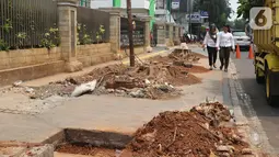 Pejalan kaki melintas di pinggir bekas tebangan pohon, di trotoar kawasan Cikini, Jakarta, Selasa (5/11/2019). Dinas Kehutanan DKI Jakarta menebang pohon di seberang Stasiun Cikini dan akan mengganti pohon angsana dengan yang tidak merusak konstruksi pedestrian. (Liputan6.com/Herman Zakharia)