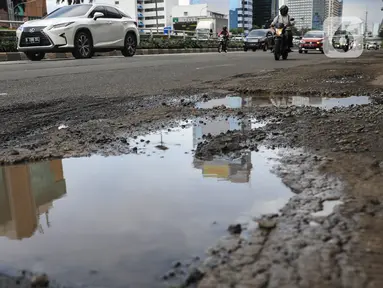 Sejumlah pengendara saat melintas dekat jalan yang berlubang di kawasan Gatot Subroto, Jakarta, Kamis (18/11/2021). Memasuki musim hujan yang turun hampir setiap hari membuat sejumlah ruas jalan rusak dan tergenang sehingga mengakibatkan jalan berlubang. (Liputan6.com/Johan Tallo)