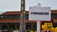 Karakter Lego berpose  di depan sebuah menara lego setinggi 35.50 meter, Itali, Minggu (21/6/2015).  Menara ini dibangun oleh ribuan relawan menggunakan sekitar 580.000 lego dan mendapat sertifikat rekor dunia dari Guinness. (AFP Photo/Giuseppe Cacace) 