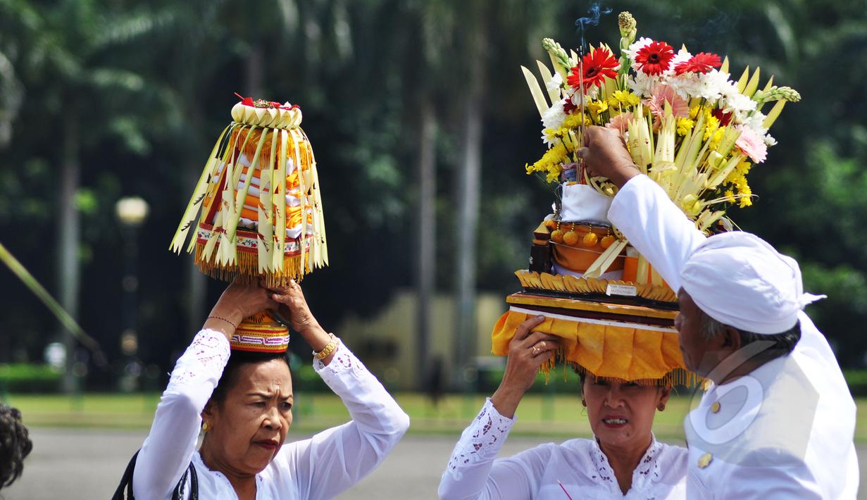 Umat Hindu menyalakan dupa di atas sesajen saat persiapan upacara Tawur Agung Kesanga di Silang Monas, Jakarta, Jumat (20/3/2015). Upacara tersebut untuk membersihkan jagat raya sebelum pelaksanaan Nyepi esok harinya. (Liputan6.com/Faizal Fanani)