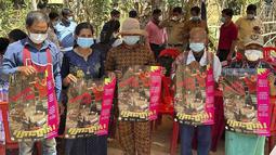 Penduduk desa Kamboja memegang poster untuk menyebarkan kesadaran akan ancaman virus H5N1 saat para ahli kesehatan berusaha mendidik mereka untuk menjaga kesehatan di Prey Veng, provinsi timur Kamboja, Kamis (23/2/2023). Gadis kecil di Kamboja itu jatuh sakit pada 16 Februari lalu dengan menderita demam, batuk dan sakit tenggorokan,  kemudian meninggal di rumah sakit, kata Departemen Pengendalian Penyakit Menular Kamboja pada Rabu. (Cambodia Ministry of Health via AP)