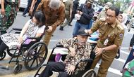 Gubernur DKI Jakarta Anies Baswedan mendorong penyandang disabilitas berkursi roda saat meresmikan pelican crossing di Halte Transjakarta Bank Indonesia (BI), Jakarta, Selasa (4/9). (Liputan6.com/Immanuel Antonius)