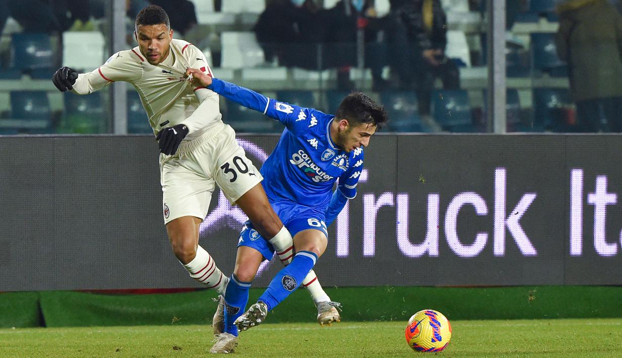 Bek Empoli, Fabiano Parisi (kanan) menahan gelandang AC Milan Junior Messias selama pertandingan Liga Serie A Italia di Stadion Carlo Castellani di Empoli, Italia, Kamis (23/12/2021). Kemenangan ini membuat AC Milan berada di posisi kedua klasemen dengan 42 poin. (AFP/Andreas Solaro)