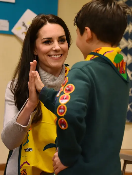 Kate Middleton tos dengan seorang anak setelah berhasil membuat rekayasa pemberian pertolongon pertama dalam acara Cub Scout Pack di Kings Lynn, Inggris (14/12). (Reuters/Ben Stansall/Pool) 
