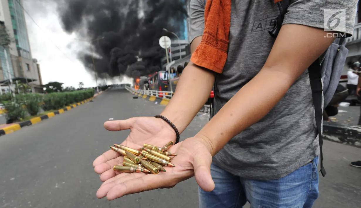 Seorang warga menunjukkan peluru dari kendaraan Polisi yang terbakar di Jalan Brigjen Katamso, Slipi, Jakarta, Rabu (22/5/2019). Belum diketahui penyebab terbakarnya dua bus yang terparkir bersama bus polisi lainnya dilokasi tersebut. (merdeka.com/Arie Basuki)