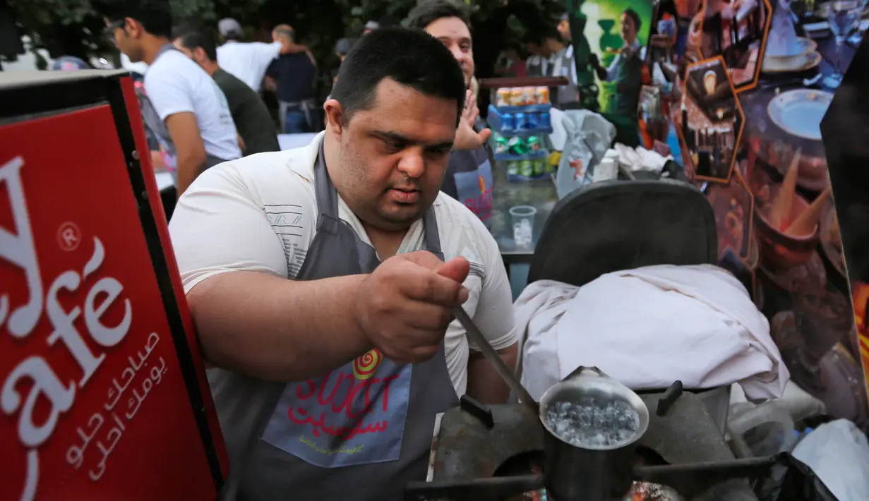 Seorang anak down syndrome menyiapkan minuman di kedai kopi Sucet  selama festival "Sham gather us" di Damascus, Suriah (11/7). Enam belas anak laki-laki dan perempuan down syndrome bekerja di Cafe Sucet melayani pelanggan. (AFP Photo/Louai Beshara)