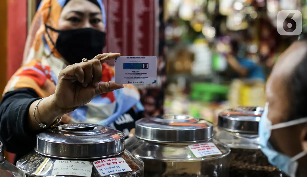 Pedagang menunjukan stiker sertifikat vaksin Covid-19 di Pasar Santa, Jakarta, Minggu (5/9/2021). Berbagai upaya dilakukan pedagang Pasar Santa untuk menarik pelanggan di masa PPKM level 3, salah satunya dengan memasang stiker sertifikat vaksin Covid-19 di beberapa ruko. (Liputan6.com/Johan Tallo)