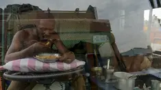 Seorang sopir makan di sebuah truk yang diparkir di terminal di Chennai (19/9/2019). Layanan transportasi darat menyerukan pemogokan satu hari untuk memprotes kenaikan pinalti di bawah Undang-undang Kendaraan Bermotor (Amandemen) yang baru. (AFP Photo/Arun Sankar)