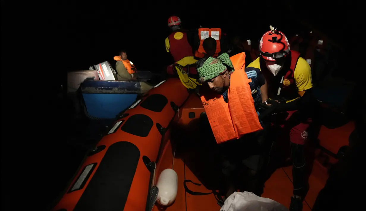 Penjaga pantai LSM Spanyol Open Arms menyelamatkan para migran dari perairan terbuka selama operasi di Laut Mediterania Minggu malam, 18 September 2022. Sekitar 200 migran dari negara-negara Suriah dan Afrika diselamatkan oleh organisasi tersebut. (AP/Petros Karadjias)