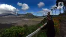 Seorang warga setempat yang berprofesi sebagai petani melihat aktivitas wisatawan dengan latar belakang Gunung Bromo. (merdeka.com/Arie Basuki)