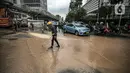 Petugas membersihkan jalan dari genangan air akibat kebocoran saluran pipa air di kawasan Bundaran Hotel Indonesia (HI), Jakarta, Selasa (11/10/2022). Kebocoran pipa air diduga terimbas proyek revitalisasi Halte Bundaran Hotel Indonesia. (Liputan6.com/Faizal Fanani)