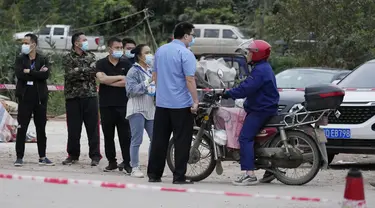 Petugas pemerintah mengontrol akses di pintu masuk desa Lu mengarah ke lokasi jatuhnya pesawat China Eastern di Guangxi, China barat daya, Selasa (23/3/2022). Kecelakaan pesawat dengan 132 orang di dalamnya itu memicu api yang cukup besar dan terlihat pada citra satelit NASA. (AP Photo/Ng Han Guan)