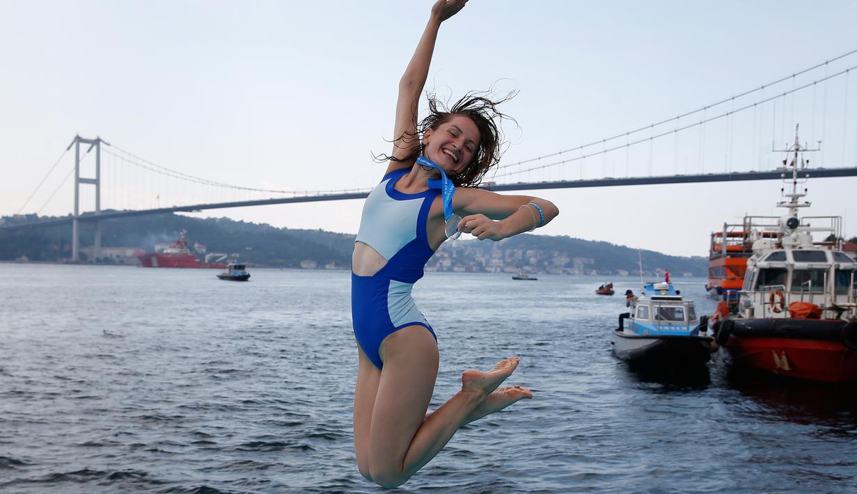 Seorang Atlet renang wanita bergembira setelah mengikuti lomba renang dari Asia hingga Eropa di Selat Bosphorus ke-30, Istanbul, Turki, (22/7). (AP Photo/Lefteris Pitarakis)