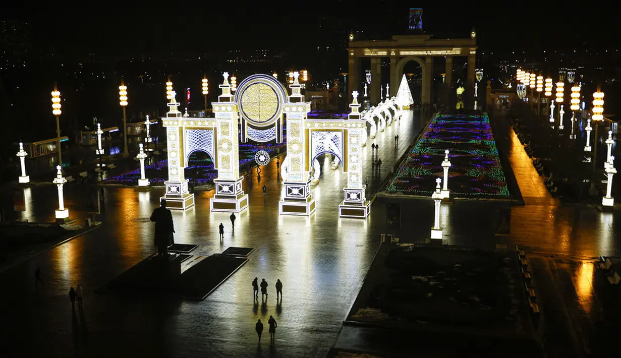 Orang-orang berjalan di VDNKh (Pameran Prestasi Ekonomi Nasional) yang didekorasi untuk perayaan Natal dan Tahun Baru di Moskow, Rusia, Jumat (27/11/2020). Area tersebut terbuat dari lapisan es buatan lebih dari 20.000 meter persegi. (AP Photo/Alexander Zemlianichenko)