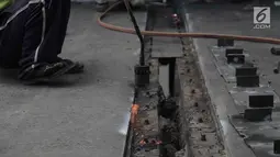 Para pekerja memperbaiki aspal di flyover Kemayoran yang mengalami kerenggangan, Jakarta, Sabtu (5/1). Hal itu disebabkan rusaknya sambungan celah sambungan alias expansion joint. (Merdeka.com/Imam Buhori)