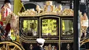 Raja Inggris Charles III dan Ratu Inggris Camilla melakukan perjalanan dengan Diamond Jubilee State Coach melewati para pengunjuk rasa yang memegang plakat "Not My King" dari kelompok anti-monarki Republik saat mereka berdemonstrasi menjelang Pembukaan Parlemen, di seberang Gedung Parlemen di London pada 7 November 2023. (HENRY NICHOLLS/AFP)
