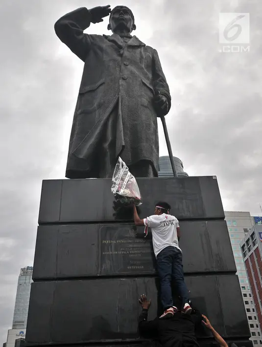 Seorang aktivis menaruh bunga di depan patung Jenderal Soedirman, Jakarta, Rabu (14/11). Aksi tabur bunga dan hening cipta ini dalam rangka memperingati Hari Pahlawan dan menghormati jasa-jasa Jenderal Soedirman. (Merdeka.com/ Iqbal S. Nugroho)
