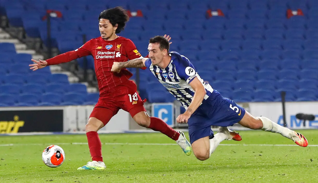 Penyerang Liverpool, Takumi Minamino merebut bola dari pemain Brighton & Hove Albion, Lewis Dunk pada lanjutan pertandingan Liga Inggris di Stadion Falmer, Kamis (9/7/2020) dini hari WIB. Liverpool berhasil kalahkan Brighton dengan skor 3-1. (AP Photo/Paul Childs,Pool)