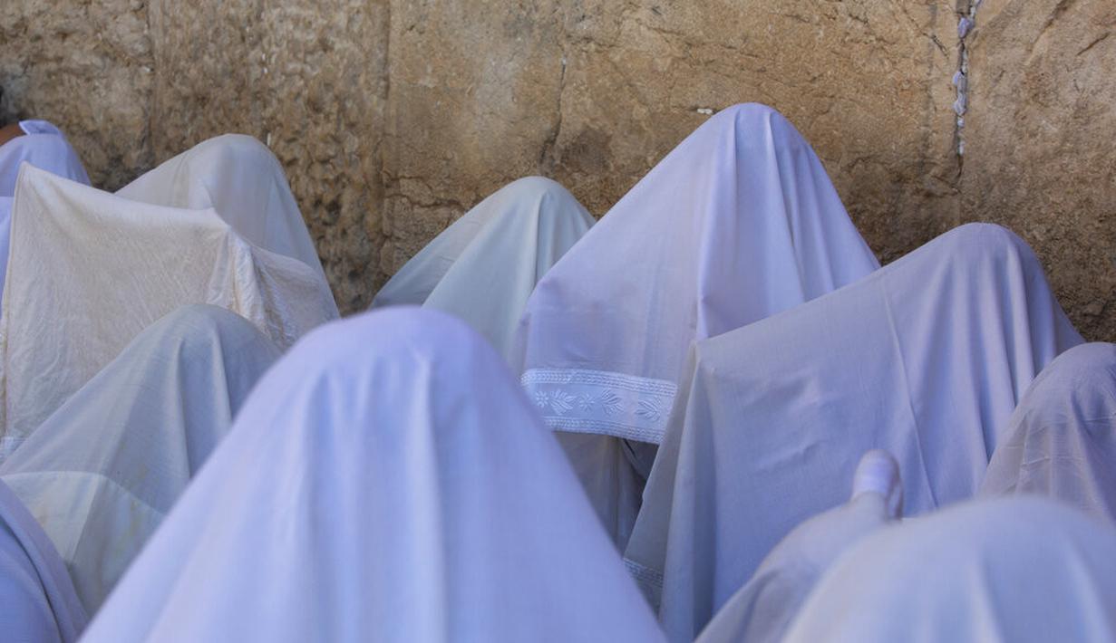Pria Yahudi ultra-ortodoks dari kasta Cohanim Priestly berdoa dengan mengenakan selendang saat mereka berpartisipasi dalam pemberkatan selama hari raya Yahudi Sukkot di Tembok Barat, situs paling suci di Kota Tua Yerusalem, Rabu (22/9/2021).  (AP Photo/Sebastian Scheiner)