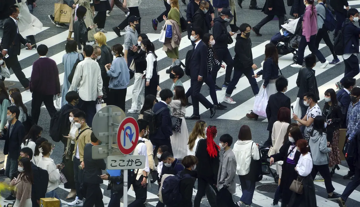 Orang-orang yang mengenakan masker pelindung untuk membantu mengekang penyebaran virus corona COVID-19 menyeberang jalan di Distrik Shibuya, Tokyo, Jepang, Rabu (7/4/2021). Tokyo mengonfirmasi lebih dari 550 kasus COVID-19 baru pada 7 April 2021. (AP Photo/Eugene Hoshiko)