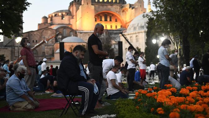 Umat Muslim melaksanakan salat di luar Hagia Sophia era Bizantium, di distrik bersejarah Sultanahmet Istanbul, Kamis, 23 Juli 2020, sehari sebelum sholat Muslim pertama di monumen tengara dalam 86 tahun setelah konversi kembali menjadi masjid. (AP Photo/Omer Kuscu)