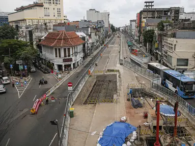 Transjakarta melintas dekat lokasi ditemukannya rel trem di lokasi pembangunan MRT Jakarta fase 2, Glodok, Jakarta, Selasa (28/12/2021). Rel trem itu ditemukan di bawah jalur TransJakarta di Jalan Pintu Besar Selatan pada Desember 2021. (Liputan6.com/Faizal Fanani)