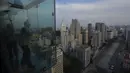 Para pekerja membersihkan kaca jendela utama di Sampa Sky Observation Deck, di Sao Paulo, Brasil pada 05 Agustus 2021. Pengunjung mengalahkan rasa takut ketinggian untuk memandangi panorama sekaligus berpose di Sampa Sky. (NELSON ALMEIDA / AFP)