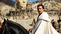Sebagai Nabi Musa, tampak Christian Bale tengah menunggang kuda dengan latar belakang orang-orang sedang membangun sebuah patung. 