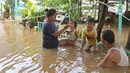 Seorang ibu menyuapi anaknya makan di tengah banjir yang melanda kawasan Cipinang Melayu, Jakarta Timur, Jumat (19/2/2021). Banjir di kawasan tersebut akibat curah hujan yang tinggi dan meluapnya air dari Kali Sunter. (Liputan6.com/Herman Zakharia)