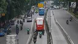 Pengendara motor melaju di belakang bus Transjakarta di kawasan Pasar Rumput, Jakarta, Rabu (20/2). PT Transportasi Jakarta akan memasang kamera pengawas (CCTV) di setiap halte untuk menerapkan tilang online atau E-Tilang. (Liputan6.com/Immanuel Antonius)