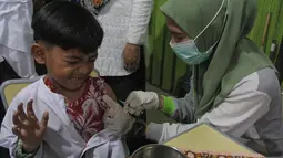Petugas kesehatan Puskesmas Batu Sari menyuntikan vaksin imunisasi Campak-Rubella (MR) ke murid kelas 1 saat pelaksanaan bulan imunisasi anak sekolah (BIAS) 2025 di SDN Batu Jaya, Kota Tangerang, Banten, Jumat (15/8/2025). (merdeka.com/Arie Basuki)