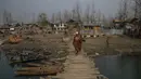 Seorang wanita Kashmir melintasi jembatan kayu di sebuah desa di pinggiran Srinagar, Kashmir yang dikuasai India (30/11/2021). Warga Kashmir menggunakan tungku tradisional ini untuk menghangatkan diri selama bulan-bulan musim dingin yang parah. (AP Photo/Dar Yasin)