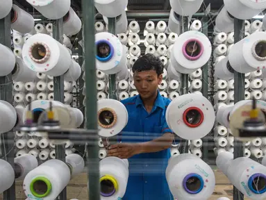 Seorang pekerja mengatur gulungan benang untuk alat tenun di pabrik Trisula Textile Industries di Cimahi, Jawa Barat pada 15 April 2025. (TIMUR MATAHARI/AFP)
