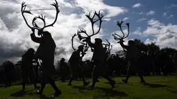 Siluet para penari saat membawakan 'Abbots Bromley Horn Dance' di desa Abbots Bromley, Inggris (11/9). Tanduk-tanduk rusa yang dipakai para penari tersebut berasal dari abad ke-11 atau sudah berusia 1000 tahun. (AFP Photo/Oli Scarff)