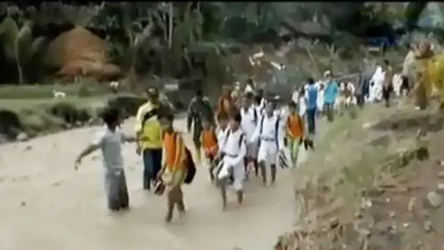 Puluhan siswa-siswi sekolah harus melepaskan sepatu sebelum melanjutkan perjalanan.