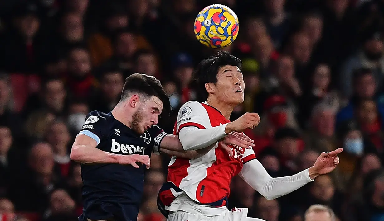 Bek Arsenal Takehiro Tomiyasu (kanan) bersaing dengan gelandang West Ham United Declan Rice (kiri) dalam laga pekan 17 Liga Inggris di Emirates Stadium, Kamis dini hari WIB (16/12/2021). Arsenal sukses kalahkan tamunya West Ham dengan skor 2-0. (Ben STANSALL/AFP)
