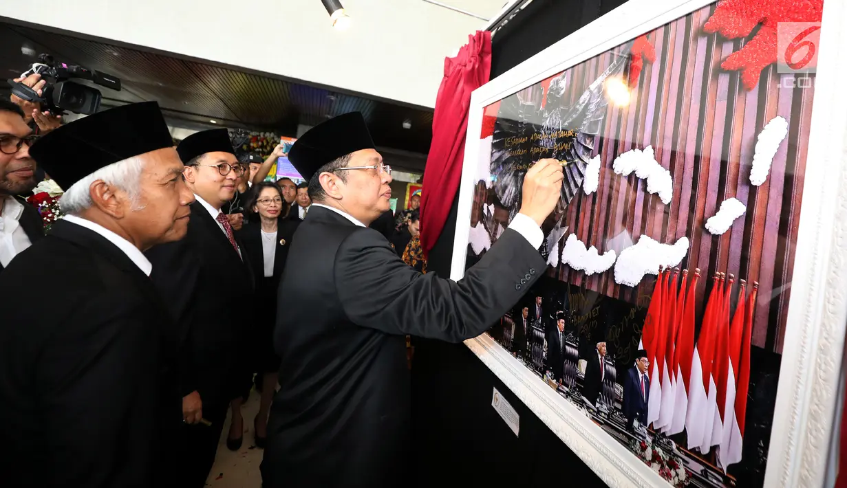 Ketua DPR Bambang Soesatyo menandantangani sebuah foto selama pameran Foto Wartawan Parlemen bertema DPR Zaman Now di Jakarta, Kamis (29/8/2019).  Pameran ini berlangsung 28 Agustus-2 September 2019. (Liputan6.com/Johan Tallo)