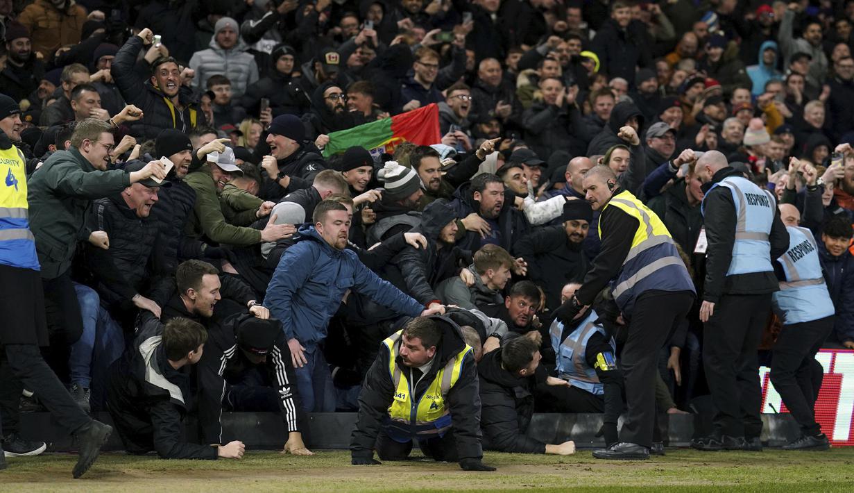 Sejumlah petugas keamanan berusaha menghalangi suporter yang akan masuk ke lapangan setelah gol ketiga Manchester United yang dicetak oleh Bruno Fernandes ke gawang Nottingham Forrest. Namun satu orang suporter pria berkacamata (kiri) berhasil lolos dari jangkauan petugas. (AP/PA/Tim Goode)