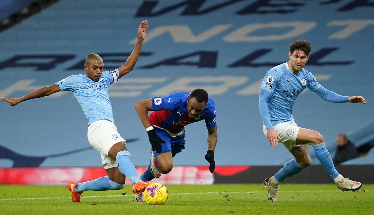 Striker Crystal Palace, Jordan Ayew (tengah) ditekel gelandang Manchester City, Fernandinho dalam laga lanjutan Liga Inggris 2020/21 di Etihad Stadium, Minggu (17/1/2021). Crystal Palace kalah 0-4 dari Manchester City. (AFP/Dave Thompson/Pool)
