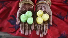 Seorang pekerja menunjukkan lilin sebelum mengemasnya untuk didistribusikan jelang Festival Cahaya Diwali di sebuah pabrik pinggiran Ahmedabad, India, 4 November 2020. (SAM PANTHAKY/AFP)