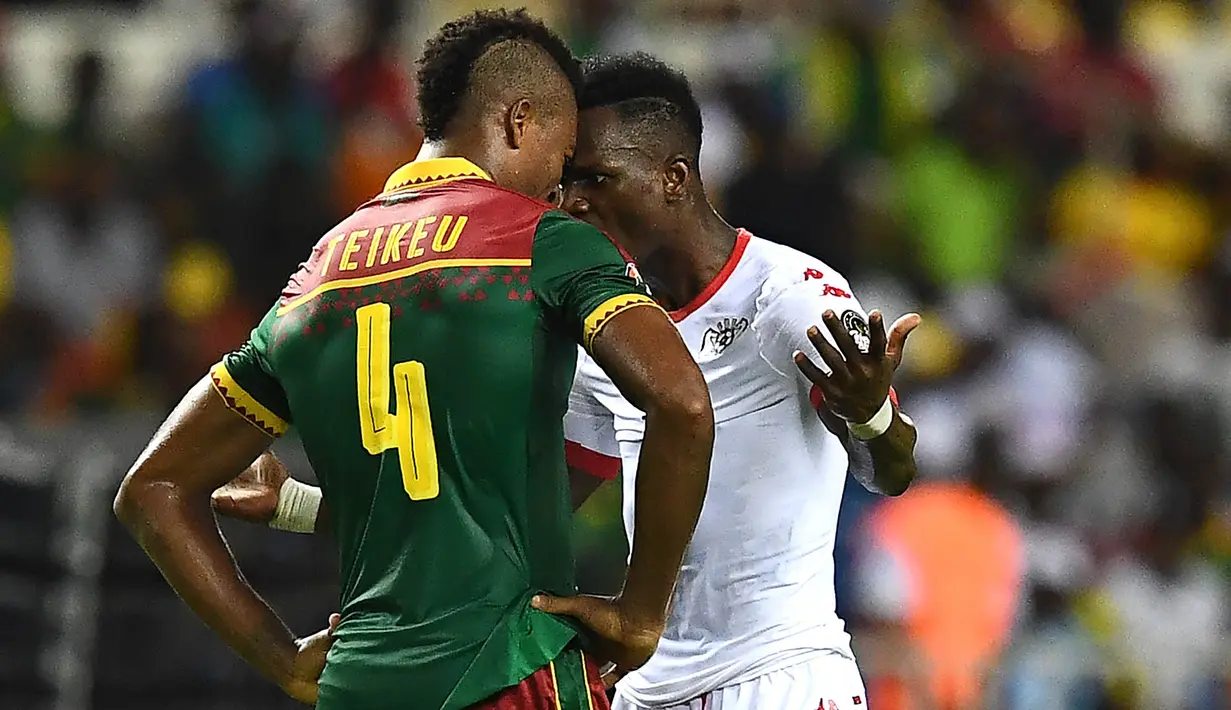 Bek Kamerun, Adolphe Teikeu, bersitegang dengan penyerang Burkina Faso, Banou Teikeu. Pada laga selanjutnya Kamerun akan menghadapi Guinea-Bissau, sementara Burkina Faso akan menantang tuan rumah, Gabon. (AFP/Gabriel Bouys)