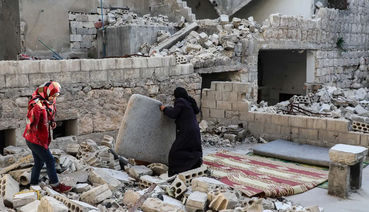 Keluarga Tareq Abu Ziad bersiap untuk berbuka puasa di tengah reruntuhan rumah mereka yang hancur setelah serangan militer pasukan pemerintah dan sekutunya di Kota Ariha, Provinsi Idlib, Suriah, Senin (4/5/2020). Muslim Suriah melewati Ramadan tahun ini masih dalam kondisi perang. (AAREF WATAD/AFP)