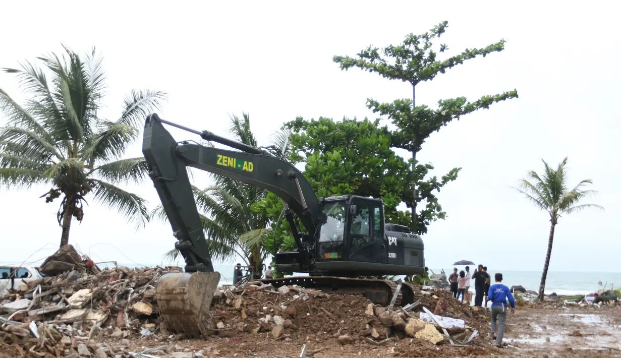 Alat berat melakukan evakuasi bangunan yang hancur akibat terjangan tsunami Selat Sunda di Carita, Banten, Selasa (25/12). Akibat tsunami yang melanda kawasan tersebut menyebakan ratusan rumah dan mobil rusak. (Liputan6.com/Angga Yuniar)
