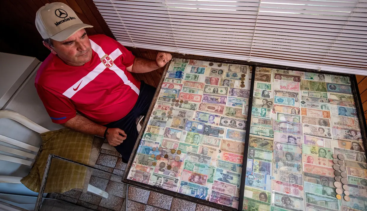 Pria Serbia, Zoran Milosevic dengan koleksi uang kertas dan koin dari seluruh dunia di rumahnya desa Pavlovci, Belgrade, 10 September 2018. Selama 36 tahun, pria yang bekerja sebagai tukang kunci itu mengumpulkan mata uang dunia. (AFP/ANDREJ ISAKOVIC)