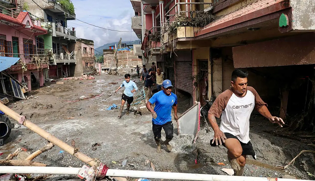 Warga setempat berjalan melewati rumah-rumah yang terendam lumpur akibat banjir bandang di Devighat, Kotamadya Bidur, Distrik Nuwakot, Nepal, Kamis, 27 Agustus 2026. (AFP/  Prabin Ranabhat)
