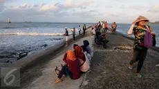  Sejumlah warga menikmati waktu senja saat matahari terbenam di Pantai Teluk Penyu Kabupaten Cilacap, Jawa Tengah,Jumat (29/7). Pantai Teluk Penyu merupakan salah satu tempat wisata andalan Kabupaten Cilacap, Jawa Tengah. (Liputan6.com/Helmi Afandi)