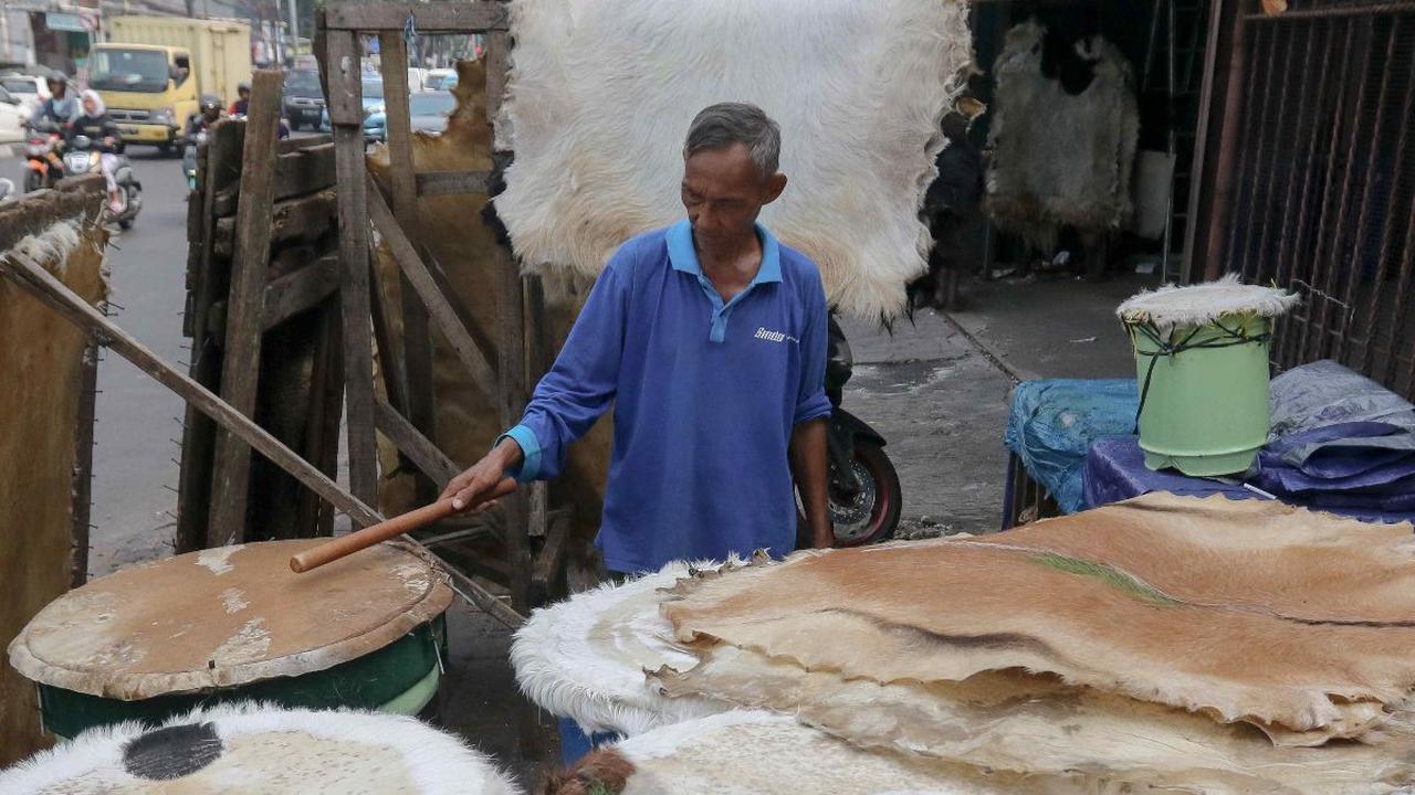 Seorang pedagang menjajal bedug buatannya yang dijual di kawasan Tanah Abang, Jakarta, Selasa (2/4/2024). Menjelang perayaan Idulfitri 1445 Hijriah, penjual bedug mengalami kebanjiran pesanan.&nbsp;Liputan6.com/Herman Zakharia