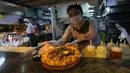 Seorang pekerja bersiap untuk menyajikan pizza dengan daun ganja kepada pelanggan di sebuah restoran di Bangkok, Thailand pada 24 November 2021. Cannabis, atau ganja, juga dimasukkan ke dalam kerak keju dan ada potongan ganja di sausnya. (AP Photo/Sakchai Lalit)