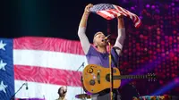 Vokalis grup band Coldplay, Chris Martin mengibarkan bendera Amerika Serikat saat menghibur para penonton di Lapangan FedEx di Landover, Md, AS (6/8). (Photo by Brent N. Clarke/Invision/AP)